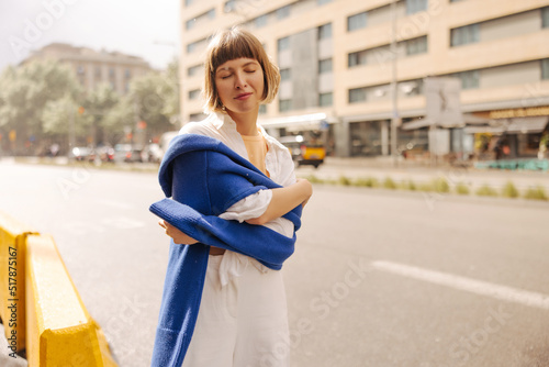 Slika na platnu Relaxed young caucasian woman closes eyes and hugs herself with hands standing in fresh air
