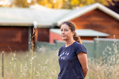 middle-aged woman outside with rustic house and wild oats in background photo