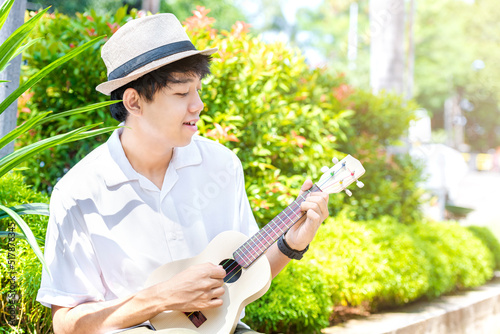 Asian man with hat playing guitar ukulele photo