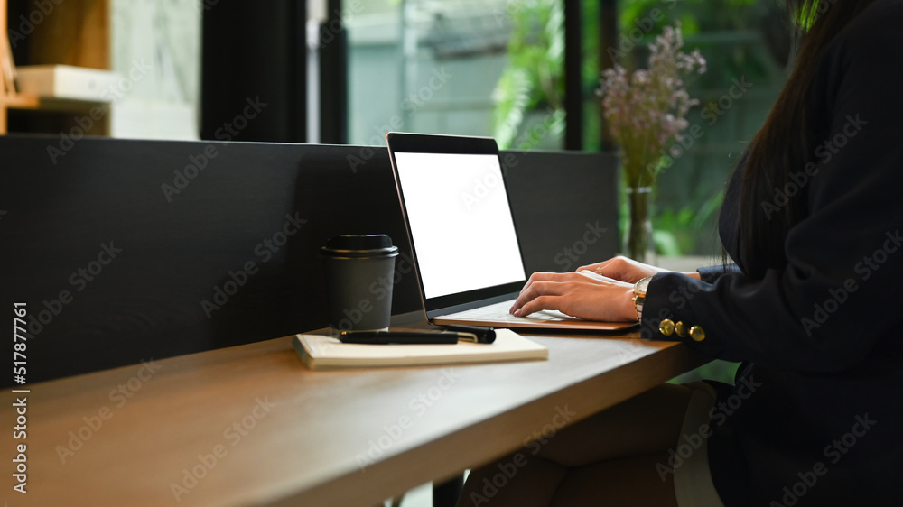 Side view young woman office worker using laptop at wooden counter bar in contemporary office Side view young woman office worker using laptop at wooden counter bar in contemporary office