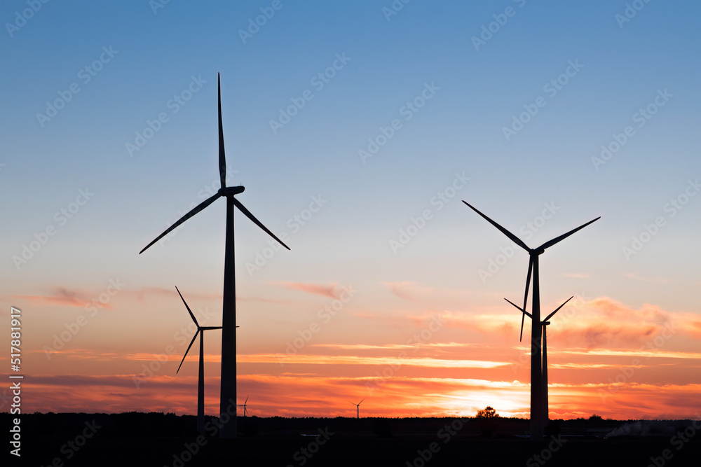 Wind farm in agricultural landscape, sunset wind turbines producing electricity, wind energy is renewable energy, clean, renewable energy source, wind turbines against the setting sun Wind farm in agricultural landscape, sunset wind turbines producing electricity, wind energy is renewable energy, clean, renewable energy source, wind turbines against the setting sun