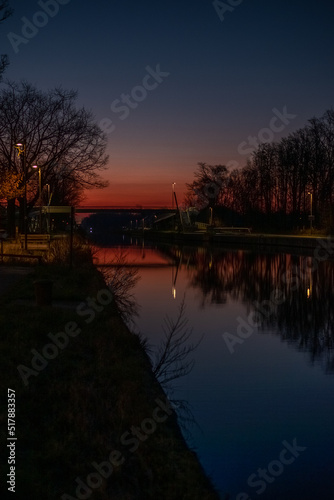 River or canal at sunset, on a background of trees. Reflection of nature on the water. High quality photo