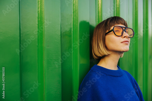 Print op canvas Cute caucasian young lady looking away through sunglasses standing on green wall background