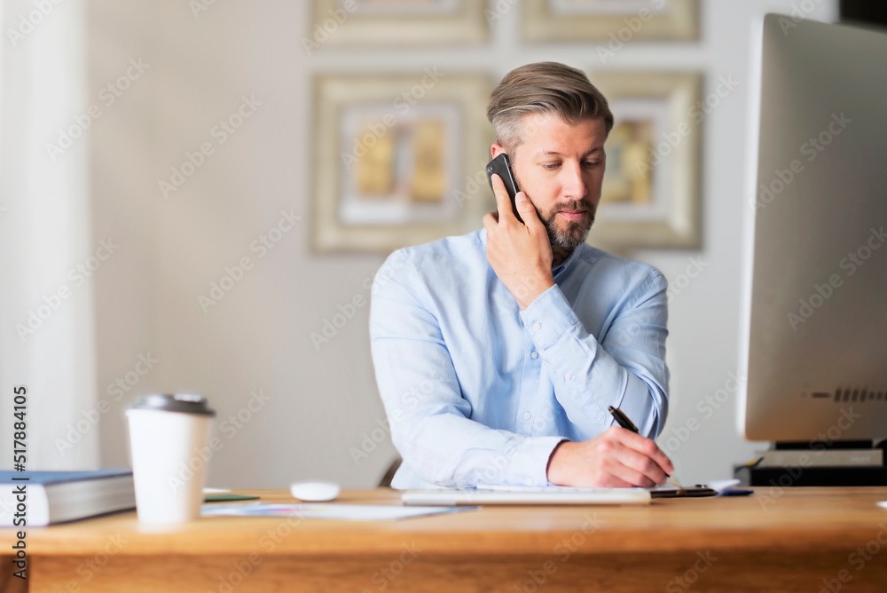 Shot of a businessman having a business call while working on computer at home Shot of a businessman having a business call while working on computer at home