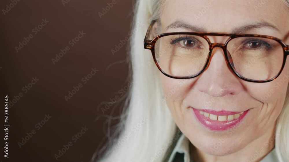 Closeup portrait of adult Caucasian woman in eyeglasses smiling at camera on studio background Closeup portrait of adult Caucasian woman in eyeglasses smiling at camera on studio background