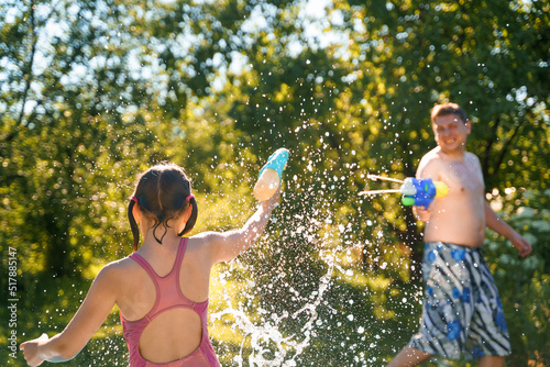 Картината върху платно Little girl in swimwear, daughter dad, daddy, father swim, play water pistols, guns in children's inflatable pool in backyard of country house