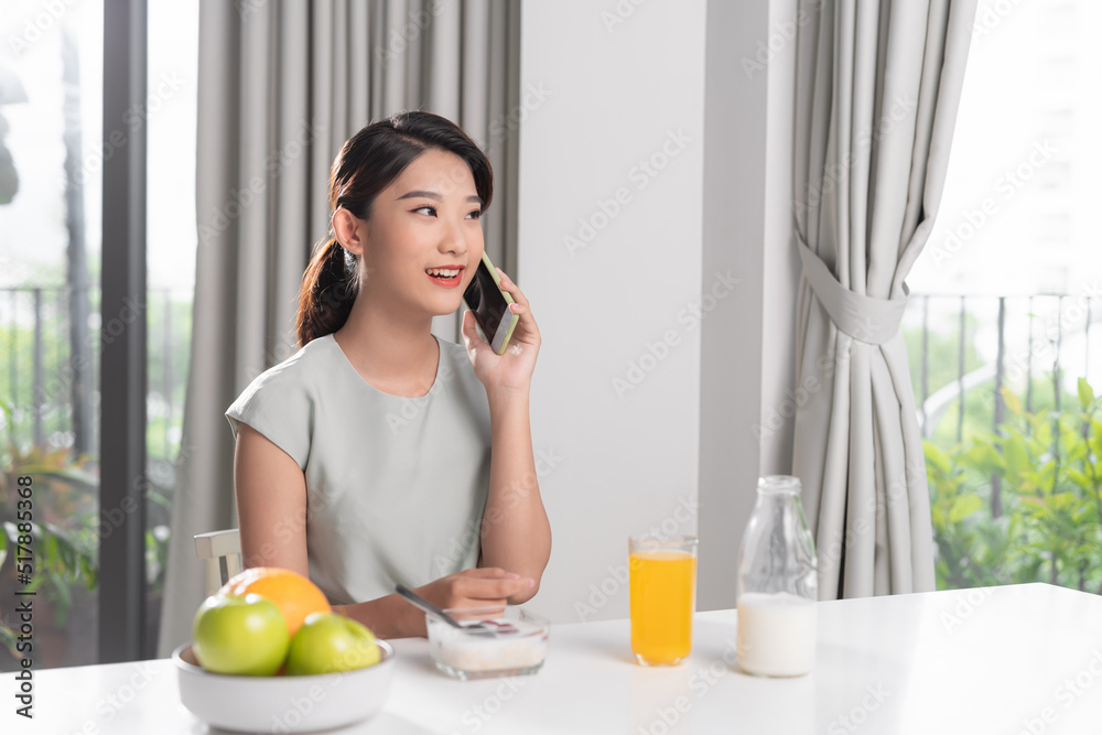 Perfect morning. Happy and positive woman eating breakfast while talking on her smartphone Perfect morning. Happy and positive woman eating breakfast while talking on her smartphone