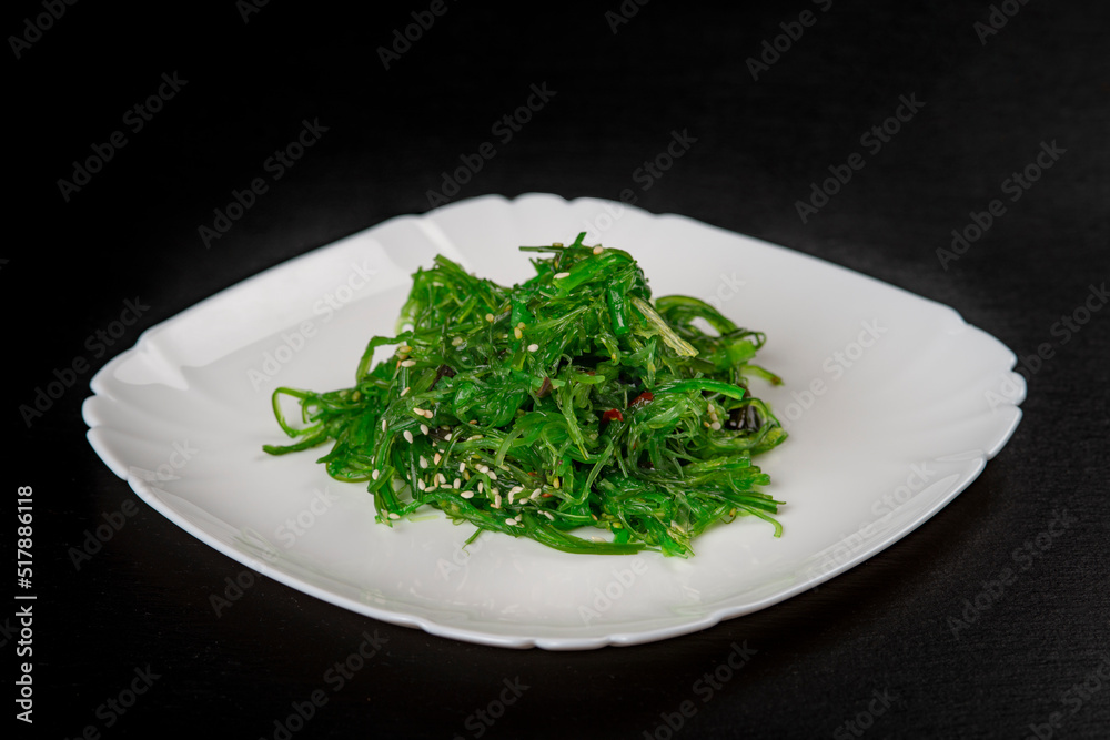 Chuka salad in a white plate on a black background .Seaweed salad -Japanese food