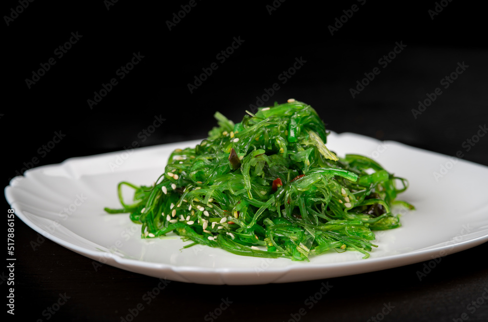 Chuka salad in a white plate on a black background .Seaweed salad -Japanese food Chuka salad in a white plate on a black background .Seaweed salad -Japanese food