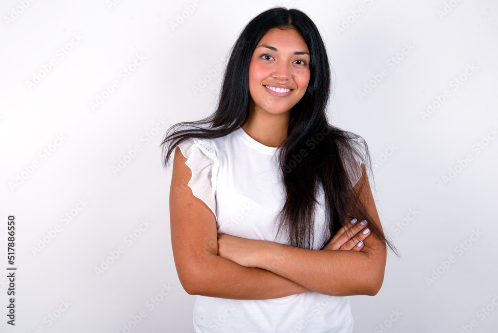 young brunette woman wearing white T-shirt standing against white background being happy smiling and crossed arms looking confident at the camera. Positive and confident person. young brunette woman wearing white T-shirt standing against white background being happy smiling and crossed arms looking confident at the camera. Positive and confident person.