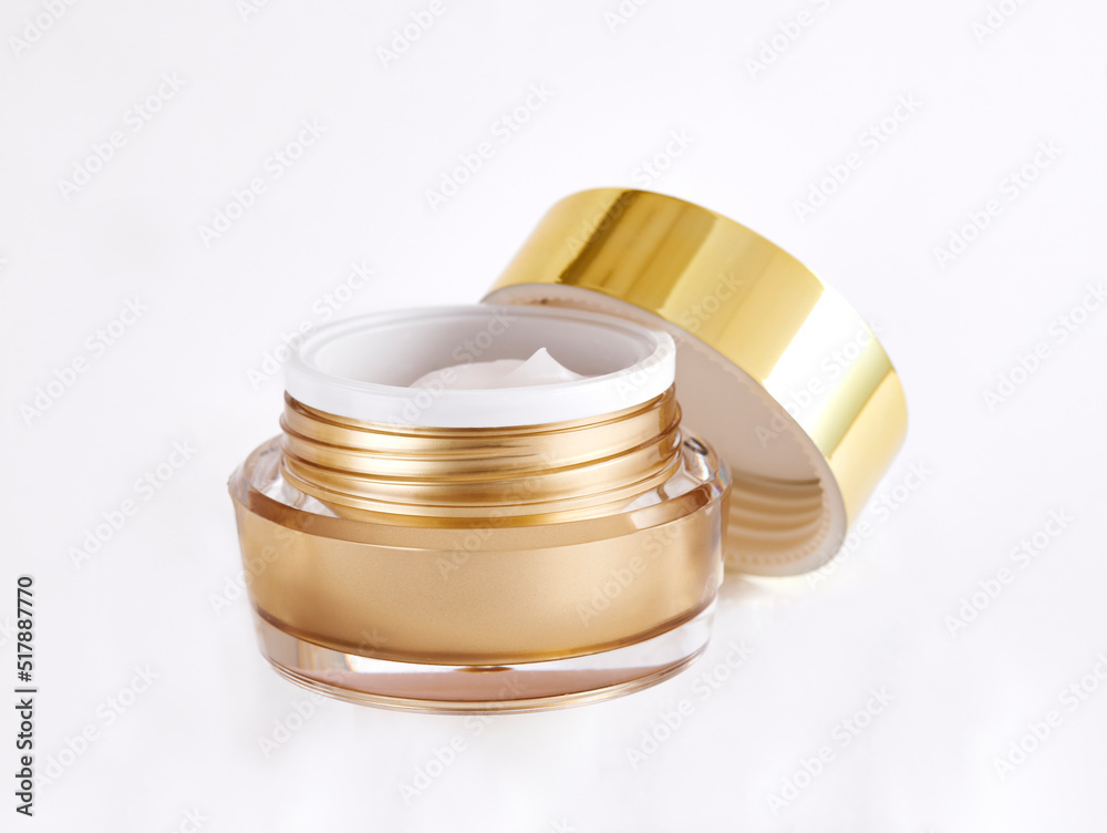 Cosmetic jar with open golden cap containing moisturizing cream for face isolated on white background Cosmetic jar with open golden cap containing moisturizing cream for face isolated on white background