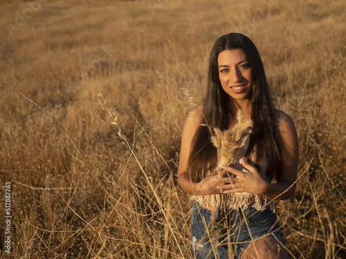 Young brunette with dry grass in field