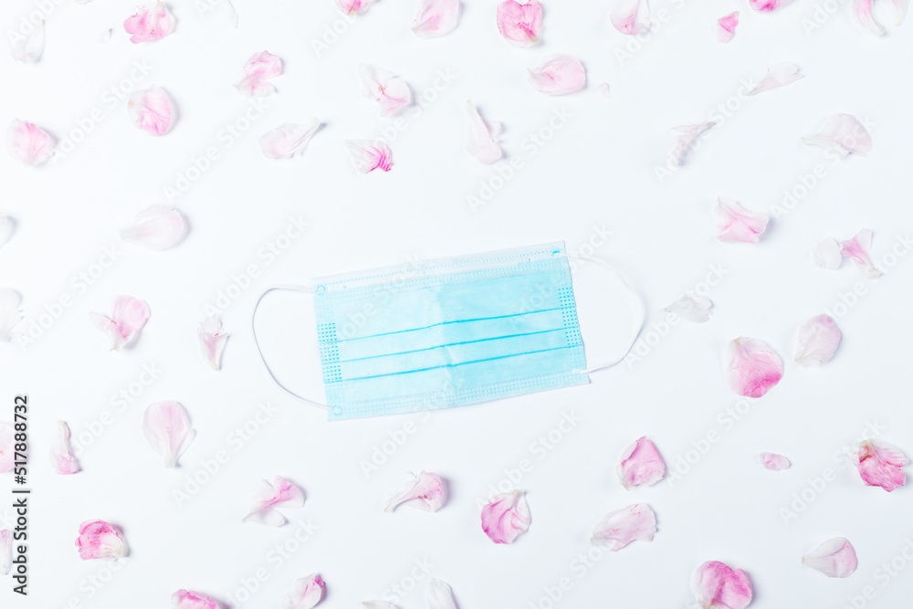 Blue medical mask among pink flower petals Blue medical mask among pink flower petals