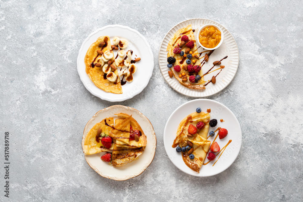 Plates with breakfast crepes with berries and bananas on light surface Plates with breakfast crepes with berries and bananas on light surface