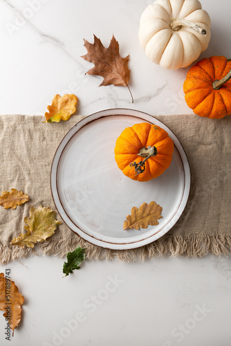 White plate autumn leaves and pumpkin holiday table setting concept