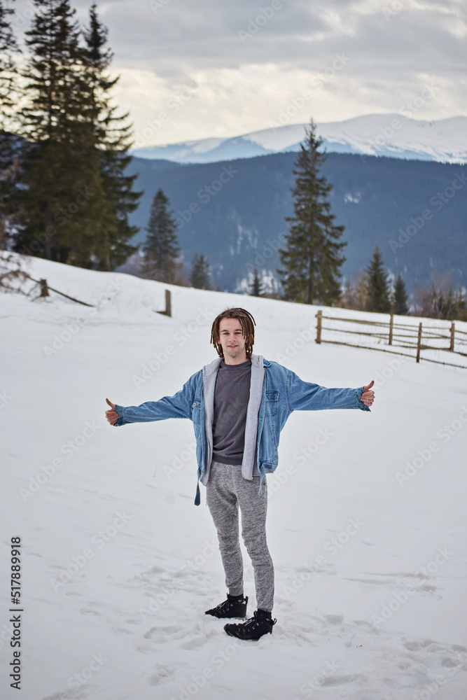 Happy attractive bearded young man standing outdoors on mountain resort