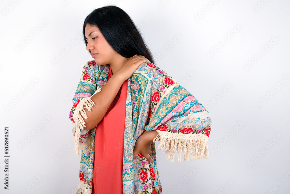 young brunette woman wearing colourful outfit standing against white background got back pain young brunette woman wearing colourful outfit standing against white background got back pain