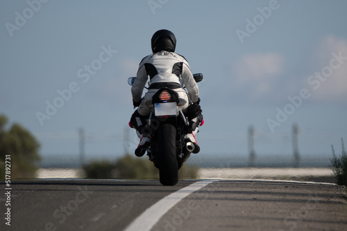 Obraz na płótnie back view of a young biker woman dressed in a leather protection suit and safety