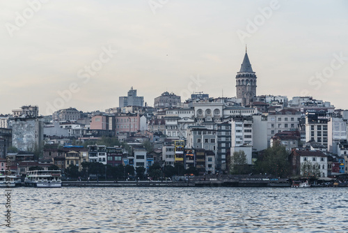 Istanbul, Turkey - April 2022: Medieval Galata Tower is famous landmark of Istanbul. Scenery of old historical place, panorama of Beyoglu district and ships on Golden Horn in the evening