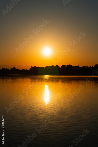 after sunrise on a lake, background forest as a silhouette