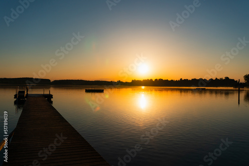 calm sunrise with a jetty, complete blue sky and no clouds, lens flares