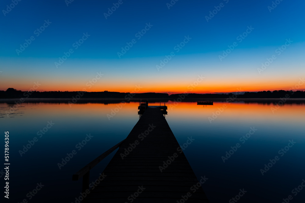 beautiful lake landscape with a red horizon, blue sky and a silhouette jetty  (Chiemsee)