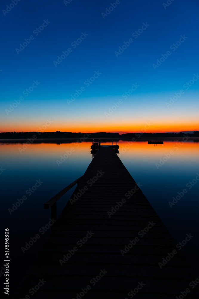 beautiful lake landscape with a red horizon, blue sky and a silhouette jetty  (Chiemsee)