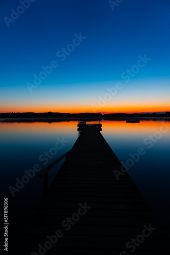 beautiful lake landscape with a red horizon, blue sky and a silhouette jetty (Chiemsee)