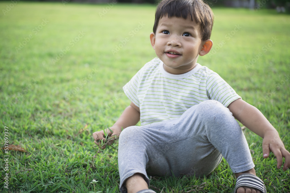 Adorable asian boy sitting and smile on green grass.Happiness boy on outdoor. Adorable asian boy sitting and smile on green grass.Happiness boy on outdoor.
