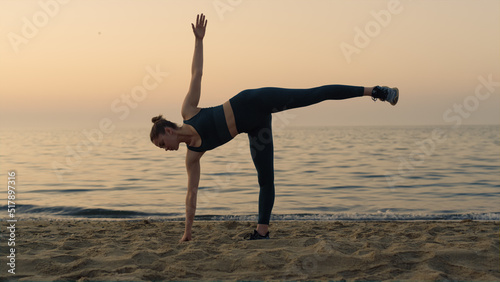 Girl making ardha chandrasana standing beach. Woman practicing half moon pose. photo