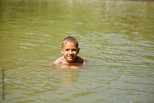 A boy is bathing in yellow river water. Rural recreation.