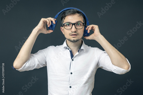 shocked young man in glasses and headphones stands on a black background