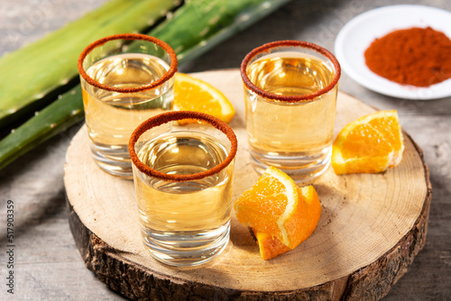 Mezcal Mexican drink with orange slices and worm salt on wooden table photo