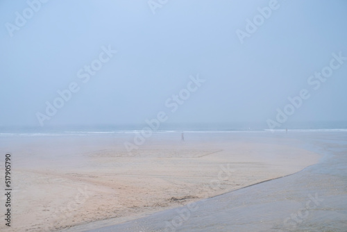 unrecognisable people enjoying the beach on a foggy day