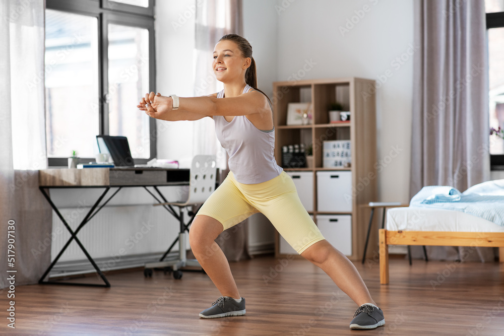 sport, fitness and healthy lifestyle concept - smiling teenage girl exercising and stretching leg at home sport, fitness and healthy lifestyle concept - smiling teenage girl exercising and stretching leg at home