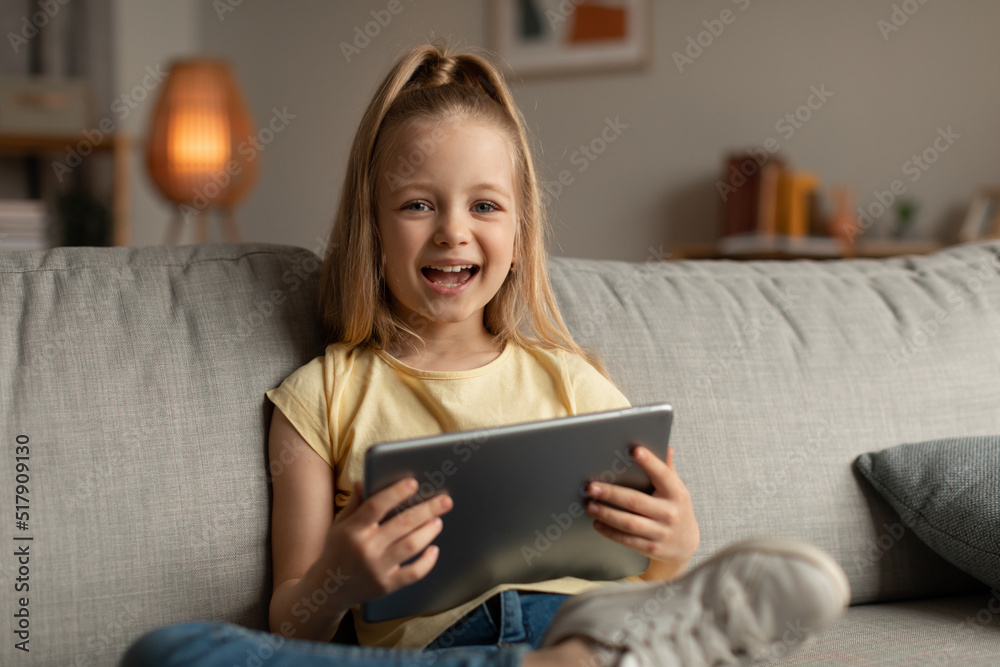 Joyful Little Girl Laughing Using Digital Tablet Sitting At Home Joyful Little Girl Laughing Using Digital Tablet Sitting At Home