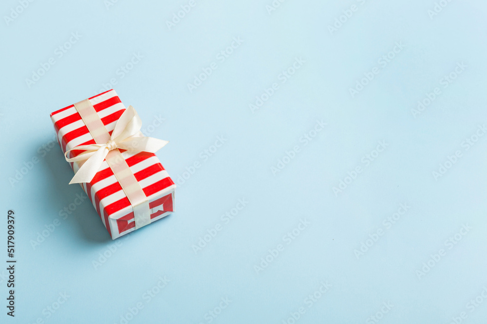 Fototapeta premium Wrapped christmas or other holiday handmade present in paper with colored ribbon. Present box, decoration of gift on table, top view with copy space