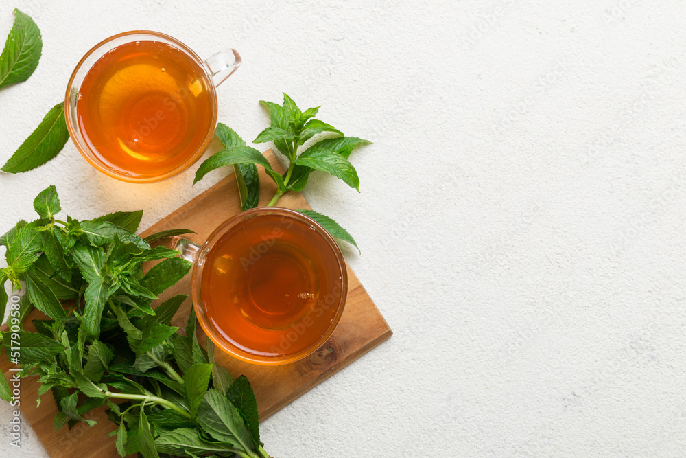 Cup of mint tea on table background. Green tea with fresh mint top view with copy space
