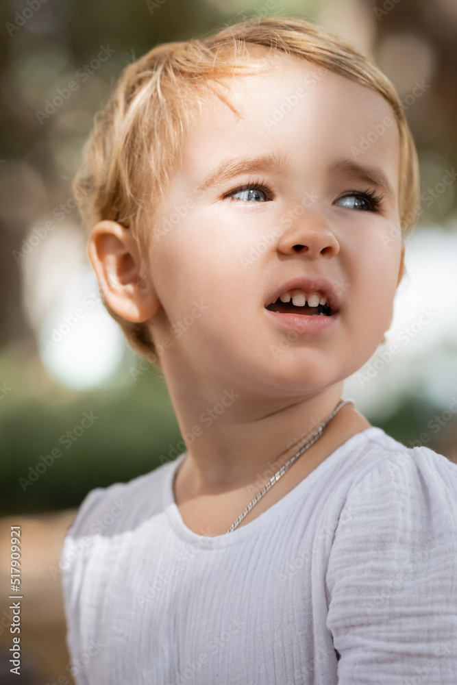 Toddler girl looking away in blurred park. Toddler girl looking away in blurred park.