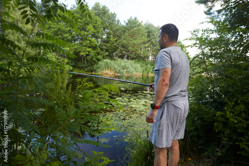 Caucasian adult man fishing on the river with beautiful view of landscape.