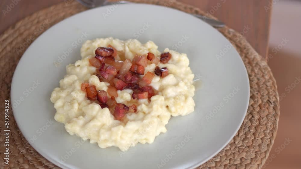 Serving Of Tasty Bryndzove Halusky Dumpling In A Plate Sprinkled With Cooked Bits Of Smoked Pork Fat. handheld shot
