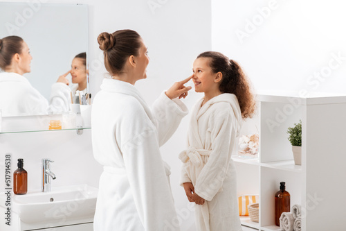beauty, hygiene, morning and people concept - happy smiling mother and daughter having fun in at bathroom