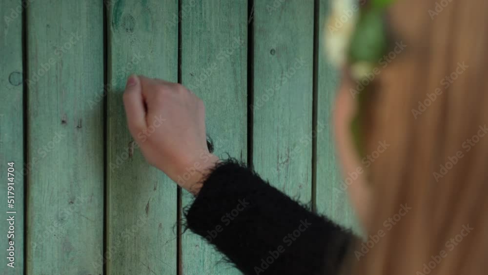 Brunette female knocking on old green rural wooden doors, back view Brunette female knocking on old green rural wooden doors, back view
