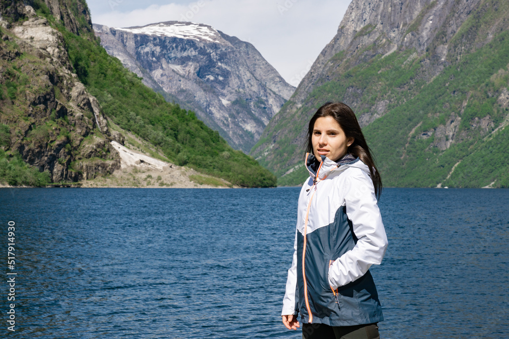 Naklejka premium Young tourist girl in the foreground and behind her the fjord with the high mountains in Gudvangen - Norway