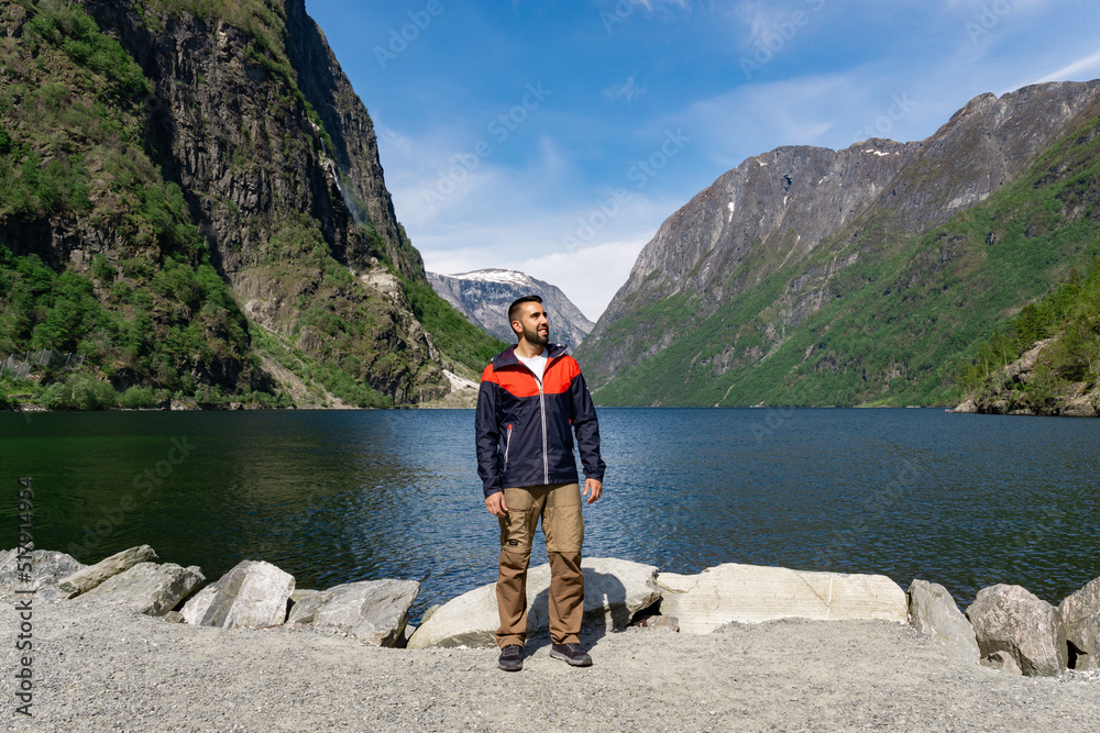 Young tourist boy at the foot of the fjord surrounded by high mountains in Gudvangen - Norway