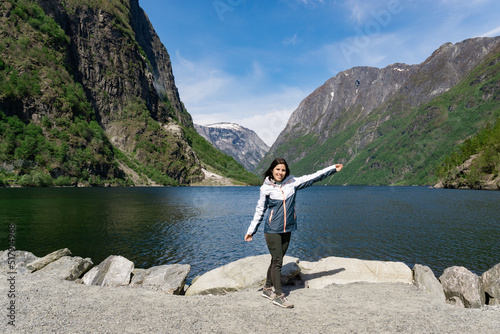 Young tourist woman at the foot of the fjord surrounded by high mountains in Gudvangen - Norway