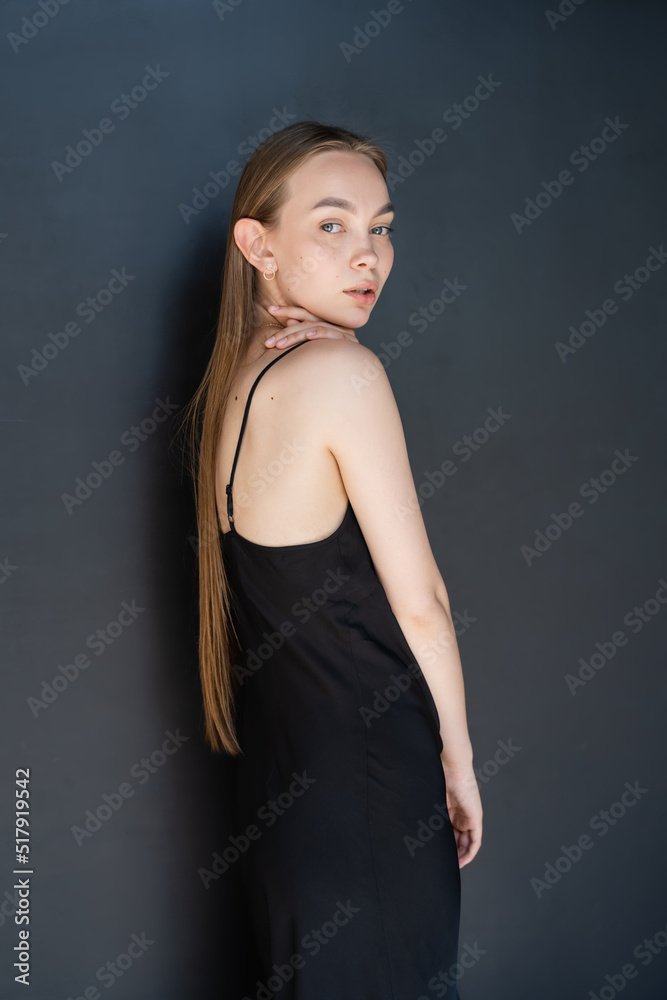 seductive long haired woman in strap dress looking at camera on black background. seductive long haired woman in strap dress looking at camera on black background.