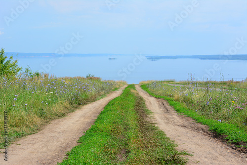 country road on top of hill going through the field to the river