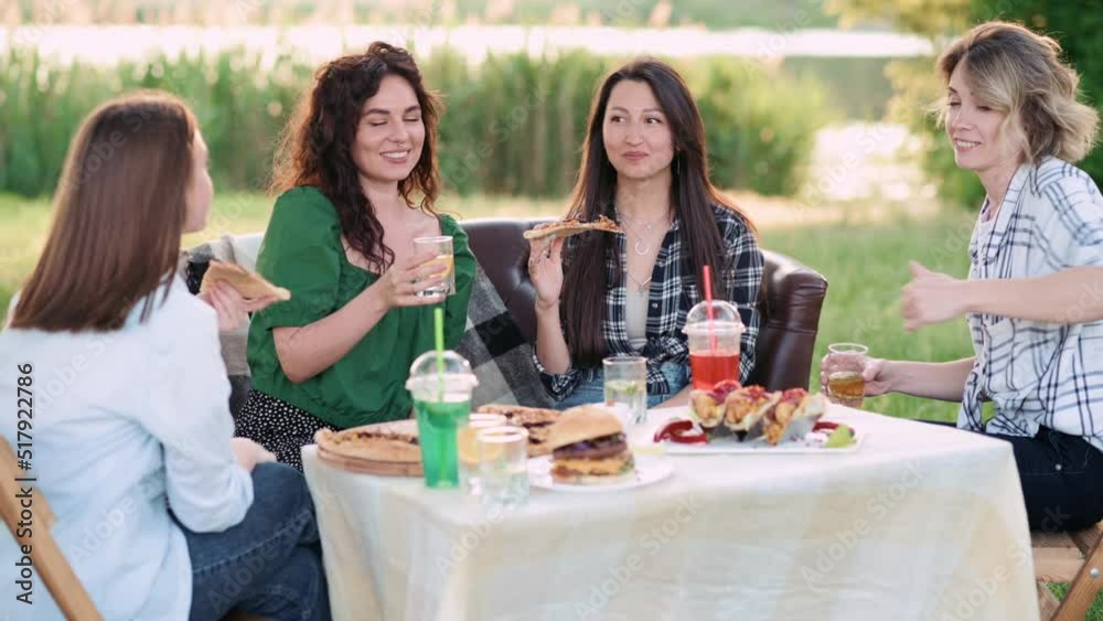 Girlfriends are having fun. Four young cheerful women eat and drink drinks in nature. Girlfriends are having fun. Four young cheerful women eat and drink drinks in nature.