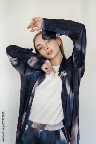 young woman in trendy gradient shirt looking at camera while posing on white background.